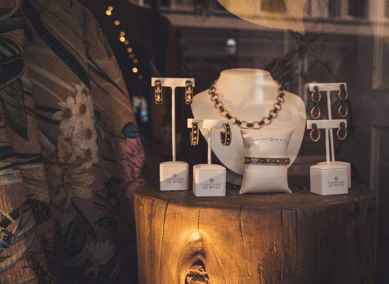 Services Showcase of elegant gold jewelry pieces on a wooden stand in a store window.