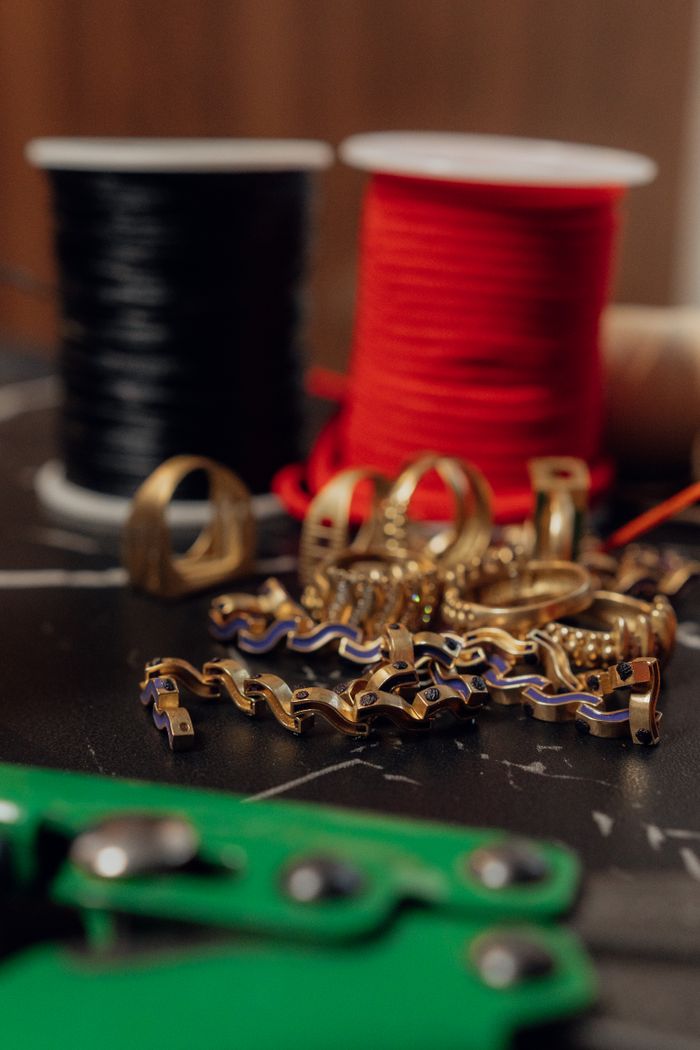 About Gold jewelry components and colorful threads on a table, perfect for crafting enthusiasts.