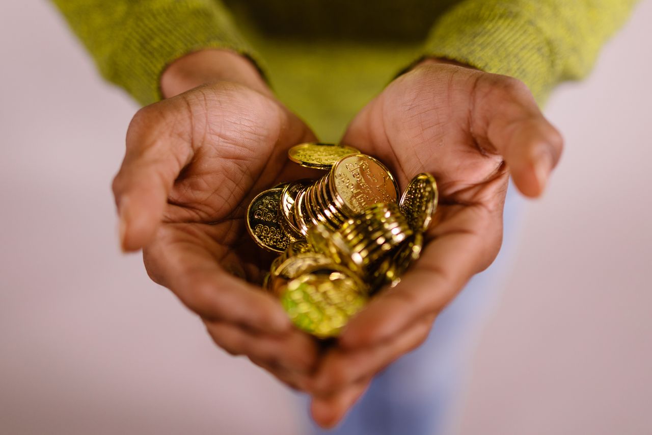 Contact Close-up of hands cupping shiny gold coins, symbolizing wealth and prosperity.